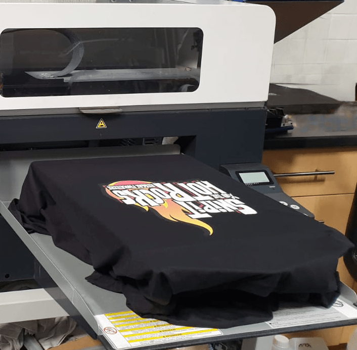 A custom printed T-shirt emerging from Buzspoke’s printing machine.